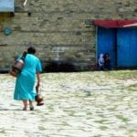 woman fetching water with hers copper vase in Lahic